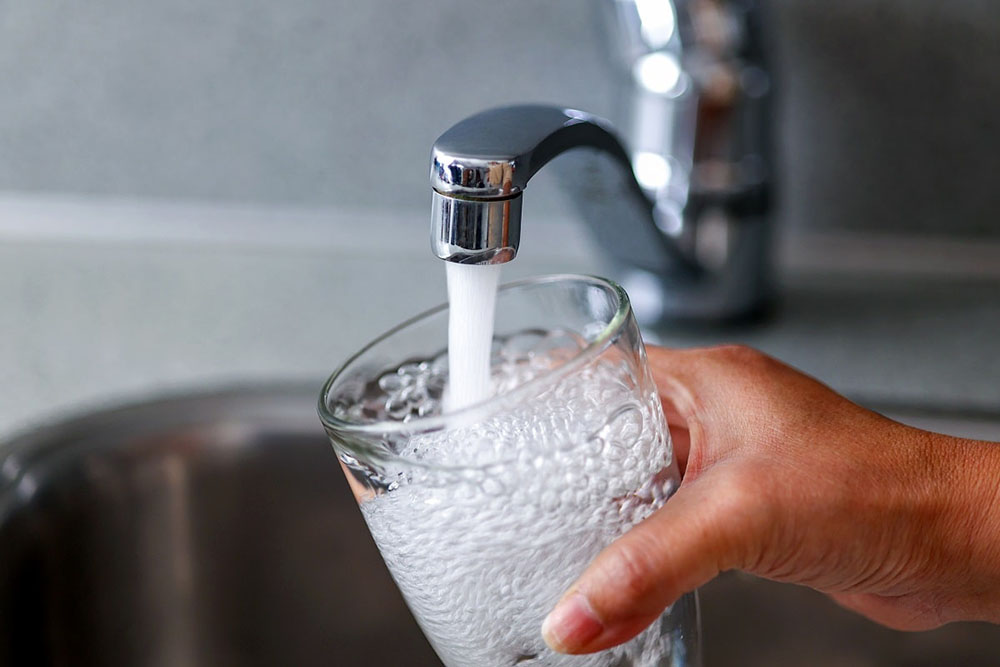 drinking glass being filled with tap water