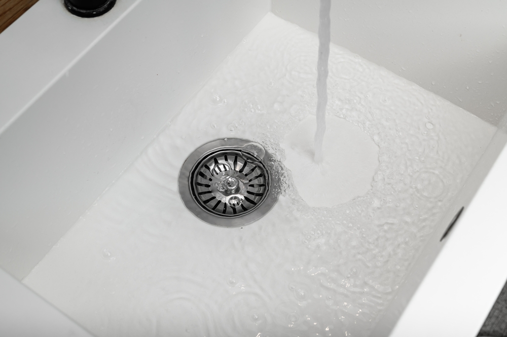  bright, clean, modern kitchen or bathroom sink with clear running water flowing effortlessly down the drain.