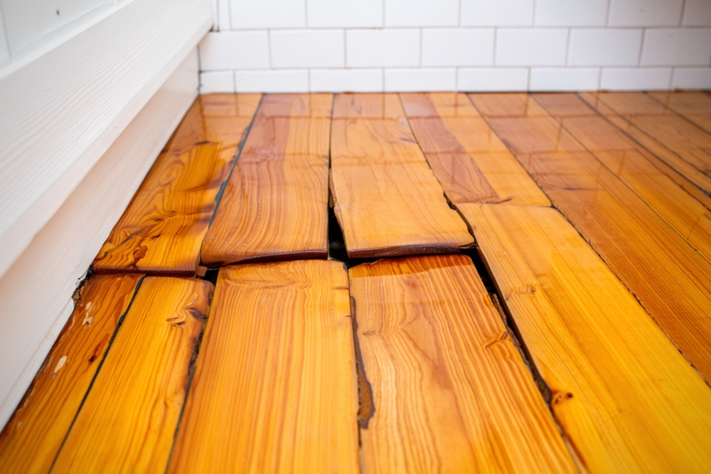 Water damage causing hardwood floorboards to cup and warp due to a hidden pipe leak near a cabinet baseboard. Water damage causing hardwood floorboards to cup and warp due to a hidden pipe leak near a cabinet baseboard.
